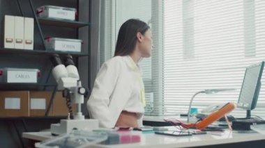 Beyaz önlüklü kadın teknisyenin servis merkezinde çalışan akıllı telefonu tamir ederken orta boy fotoğrafı.