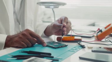 Servis merkezinde çalışırken bozuk sabit diski tamir eden tornavidayla erkek uzmanın ellerini kapatın.