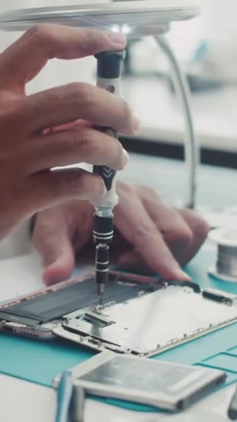 维修服务中心移动电话电池时使用螺丝刀的工程师手的垂直方向 — 图库视频影像