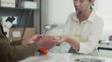 Erkek müşterinin kırık akıllı telefonu tamir merkezinde mikrofonla kadın yöneticiye verirken görüntüsü kesilmiş.