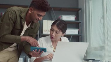 Merkezde akıllı telefon ve dizüstü bilgisayarın yardımıyla yeni yazılımı test eden iki programcının orta boy görüntüsü.