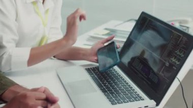Kadın teknisyen ve erkek müşterinin bilgisayardaki özel uygulamayla akıllı telefon işlerini kontrol ederken görüntülerini yukarı kaldır.