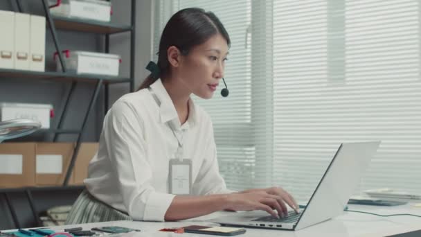 女性维修中心经理坐在笔记本电脑前 用耳机与客户进行咨询的中景照片 — 图库视频影像