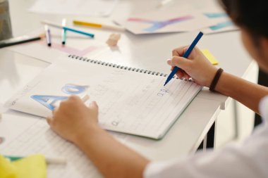 Okulda İngilizce öğrenirken el yazısı pratiği yapan kızların elleri