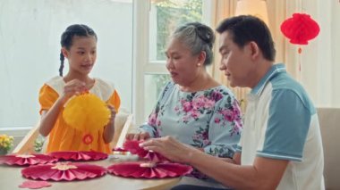 Ay 'ın Yeni Yılı' nı kutlamak için dekorasyon ve çelenk yapan çok nesilli Asyalı aile üyelerinin orta boy fotoğrafı.