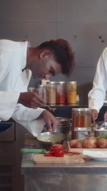 Otel restoranının mutfağında çalışırken salata sosunu kontrol ederken dikey çekim.