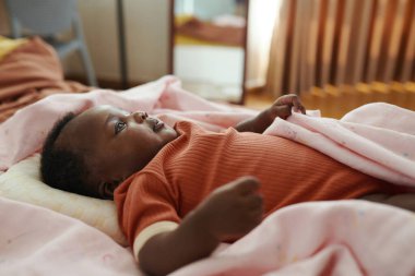 Pamuk bebek, yumuşak pembe battaniyeyle yatakta büyür.