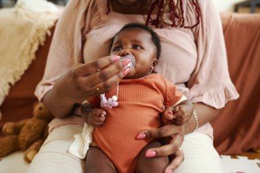 Annem neredeyse ağlayan yeni doğan bebeğe emzik veriyor.