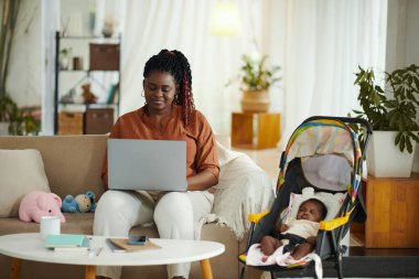 Yeni doğan bebeğin annesi kızı uyurken evde çalışıyor.
