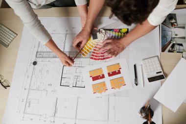 Profesyonel mimar ve mühendis müşteri için büyük bir ev üzerinde çalışıyor, planı kontrol ediyor ve boya rengini seçiyor