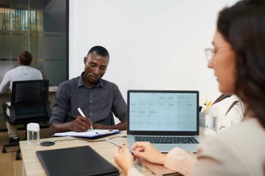 HR yöneticisi CV formunu dolduran kişi dizüstü bilgisayardaki takvimi kontrol ediyor