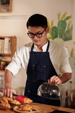 Garson, müşteri için taze kruvasan hazırlıyor.
