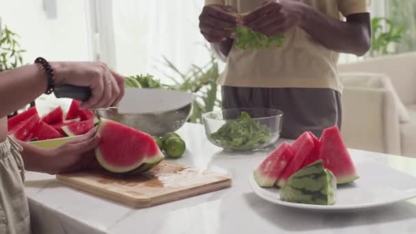 スイカを切断し レタスを引き裂く女性のクロップショット 健康的な噛み合いと自宅で夕食のために葉 — ストック動画