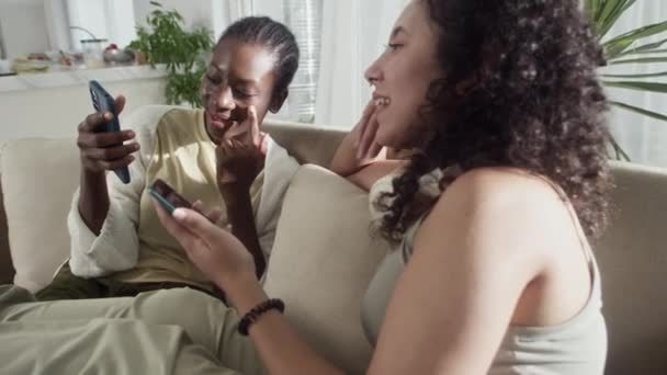 Στιγμιότυπο Σημύδες Φιλενάδες Αναπαύονται Στον Καναπέ Και Βλέπουν Βίντεο Smartphones — Αρχείο Βίντεο