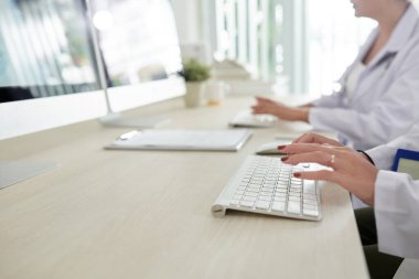 Araştırma merkezinde yeni aşı ya da ilaç üretirken bilgisayar üzerinde çalışan bilim insanlarının yakın plan görüntüleri