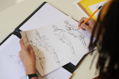 Yeni koleksiyon için taslak üzerinde çalışan moda tasarımcısının yakın plan resmi