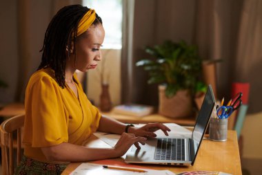 Siyah moda tasarımcısı dizüstü bilgisayardaki müşterilerin e-postalarına cevap veriyor