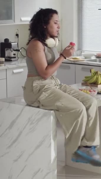 Pionowa Młoda Kobieta Rozmawiająca Jedząca Arbuza Siedzącego Przy Blacie Kuchennym — Wideo stockowe