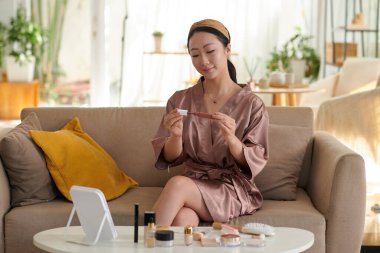 Saten bornozlu kız açılış rujunu sürüyor.