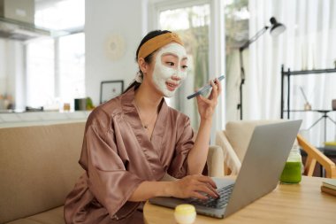 Yüzü maskeli neşeli genç bir kadın arkadaşına ya da meslektaşına sesli mesaj kaydediyor.