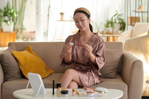 Saten bornozlu kız açılış rujunu sürüyor.