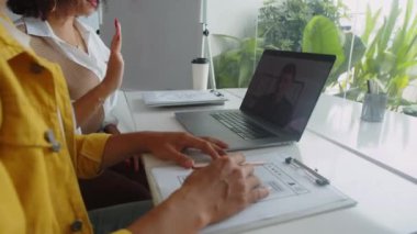 Tanımlanamayan ofis çalışanlarının video başında dizüstü bilgisayarın önünde proje yöneticisiyle konuştuğu görüntüler.