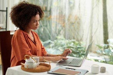 İnternet dergisi için çalışırken çay içen ciddi Latin kadın