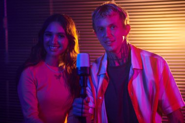 Partide mikrofonda şarkı söyleyen gülümseyen düet portresi