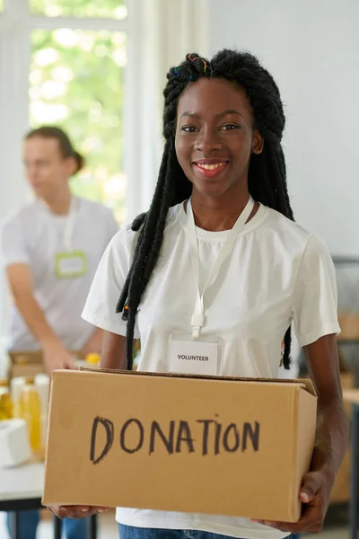 寄付された製品と箱を保持する幸せな黒人の若い女性の肖像画 — ストック写真