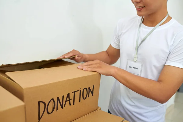 Smiling volunteer opening box with donated products
