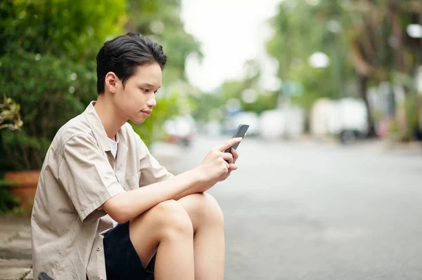 Teenager Mit Smartphone Sitzt Auf Gehweg Und Schreibt Freunden Sms — Stockfoto