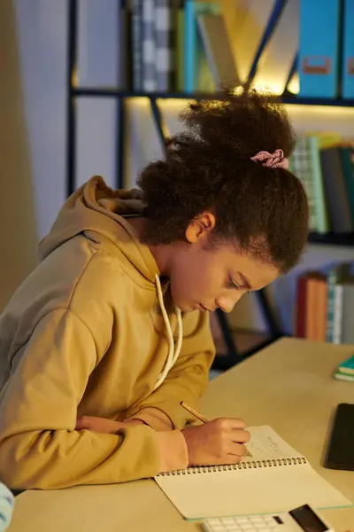 自宅で宿題をしたり 教科書で書いたりするカーリーヘアの多民族十代の少女 — ストック写真