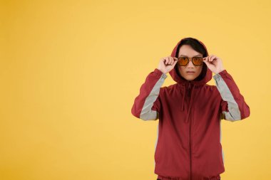 Sarı güneş gözlüğü takan atletizm ceketli ciddi bir koşucu.