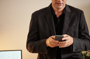 Akıllı telefondan bildirimleri kontrol eden ciddi iş adamının kırpılmış görüntüsü