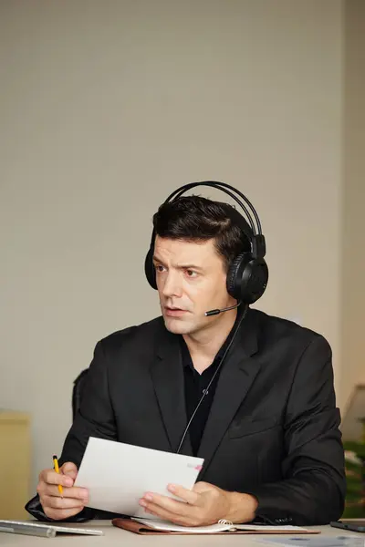 Portrait of serious entrepreneur wearing headset during distant meeting with business partners