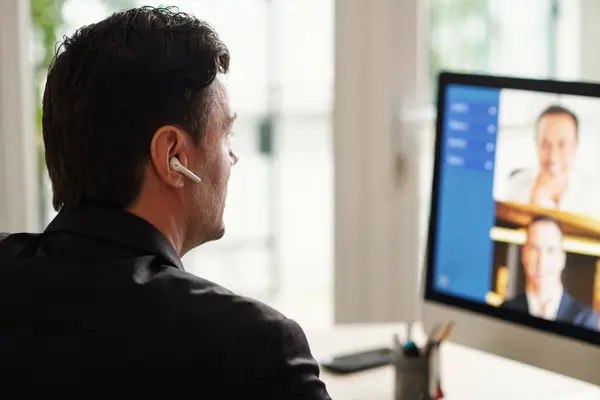 Entrepreneur attending remote meeting with colleagues, view over shoulder