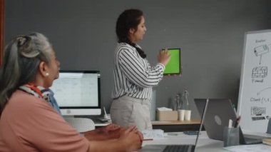 Genç bayan öğretmenin yeşil fotokopi ekran ile dijital tableti tutarken orta boy fotoğrafı.