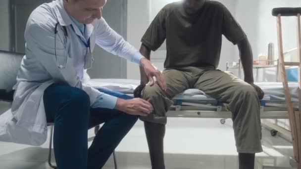 Doutor Casaco Branco Examinando Perna Quebrada Paciente Recuperado Sentado Cama — Vídeo de Stock