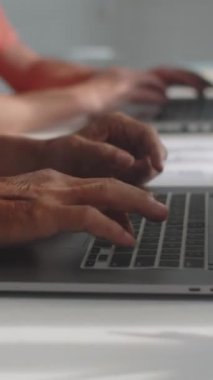 Bilgisayar dersi sırasında kablosuz dizüstü bilgisayarların klavyesinde yazan yaşlıların dikey görüntüsü