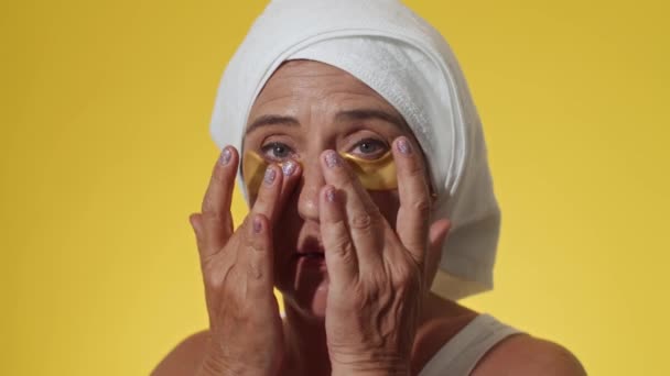 黄色の背景に隔離された目のパッチの下に適用ターバンヘアタオルの遺伝子X女性の閉鎖 — ストック動画