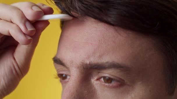 浅褐色眼睛 深色头发的中年男子用黄色背景的瓜沙工具按摩皱纹额头的剪下来的照片 — 图库视频影像