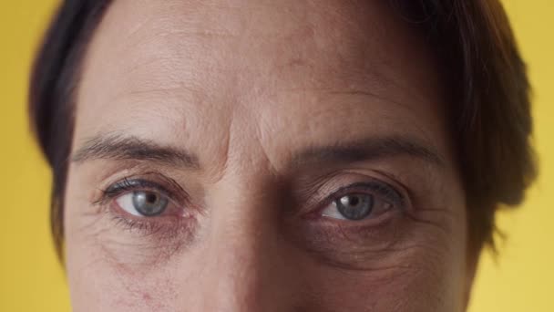 カメラを見る老化の変化を持つ成熟した女性の顔に青い目を閉じる — ストック動画