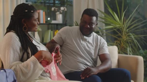中镜头 年轻的黑人准妈妈和她的丈夫在去分娩中心之前为孩子准备衣服 — 图库视频影像