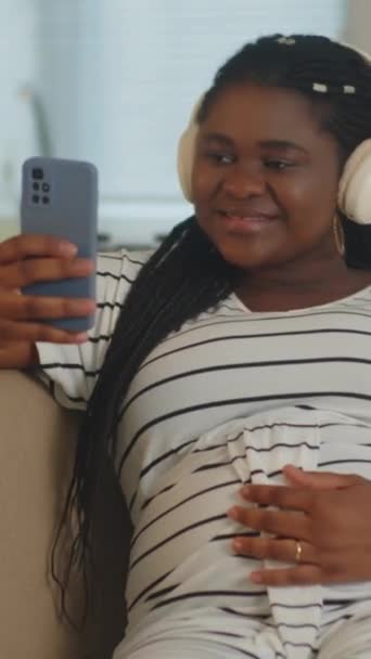 Çizgili Elbiseli Kulaklık Takmış Akıllı Telefondan Müzik Dinleyen Siyahi Bir — Stok video