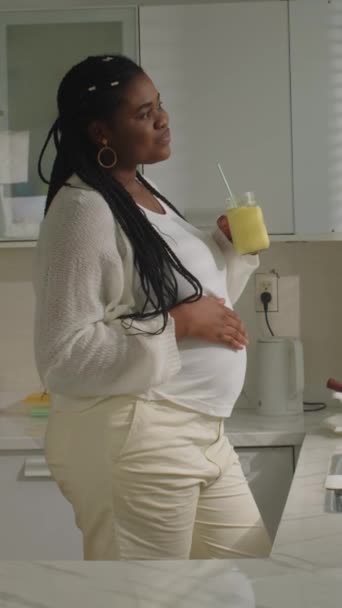 Tiro Vertical Futura Madre Afroamericana Bebiendo Batido Frutas Mirando Ventana — Vídeo de stock