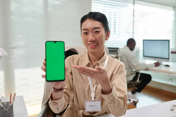 Portrait of smiling bank manager showing smartphone with green screen explaining how application works