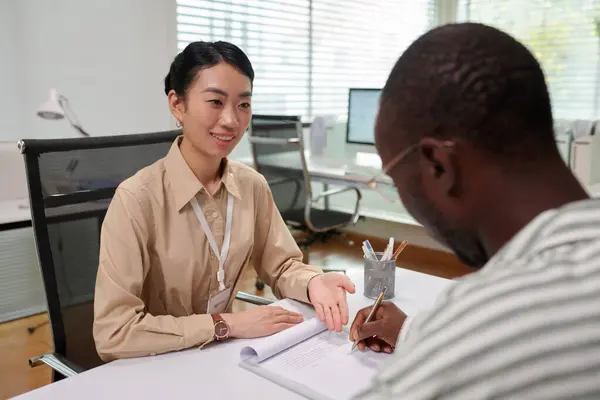 Smiling bank manager asking client to sign agreement