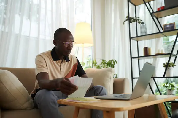 Black man checking utility bills when managing his expenses via application on laptop