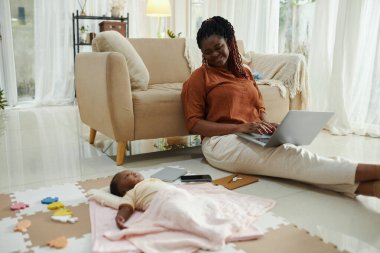 Mutlu çalışan anne, uyuyan bebeğine bakıyor.