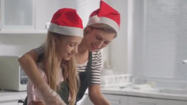 Anne, kızına Noel kurabiyeleri için hamur yoğurmayı öğretirken, mutfakta birlikte yemek pişirirken.